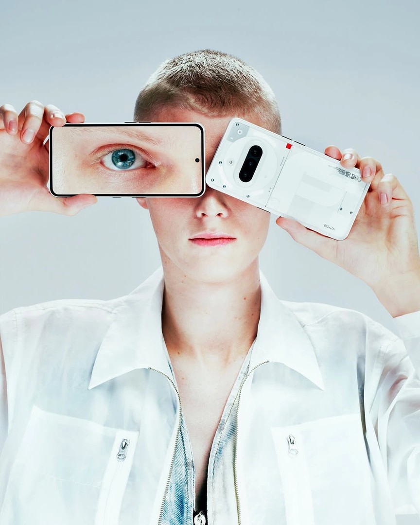 Yüzünün önünde iki telefon tutan kişi